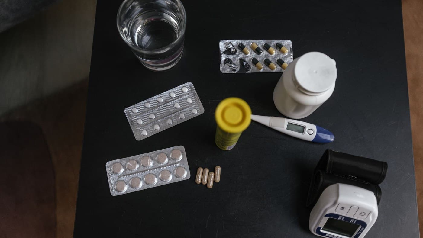 Medicamentos, termômetro e aparelho de pressão sobre uma mesa